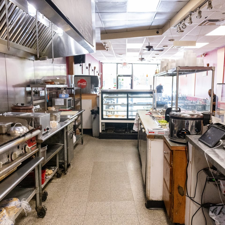 A commercial kitchen with stainless steel equipment, a display case, and a Coca-Cola machine.