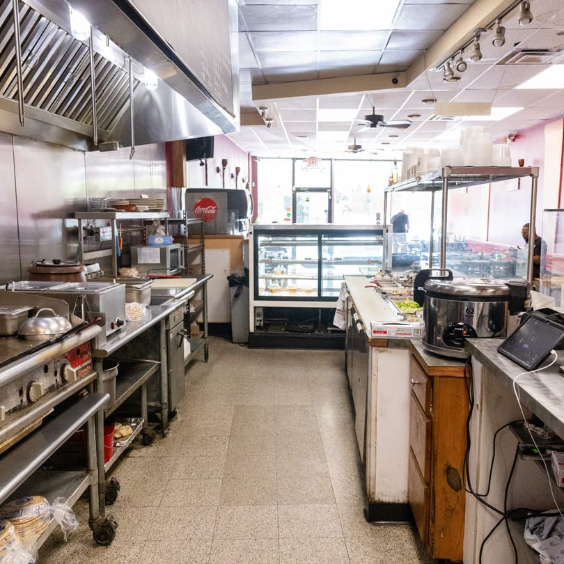 A commercial kitchen with stainless steel equipment, a display case, and a Coca-Cola machine.